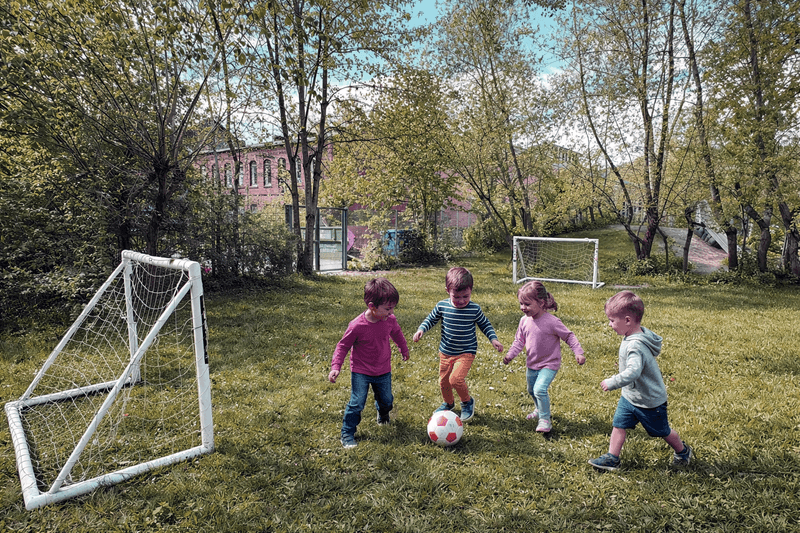 Kinder spielen Fußball im Garten