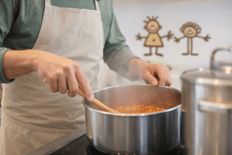 Elternteil beim Kochen am Herd